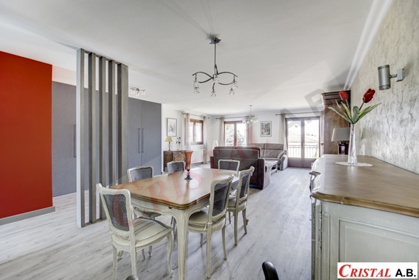 Salle à manger lumineuse avec table bois, séparateur ajouré et salon moderne ouvert. Logo Cristal A.B.