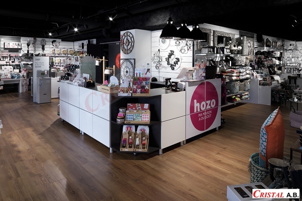 Boutique Hozo Ma Maison a du Goût : comptoir blanc, objets de décoration et luminaires noirs sur parquet.