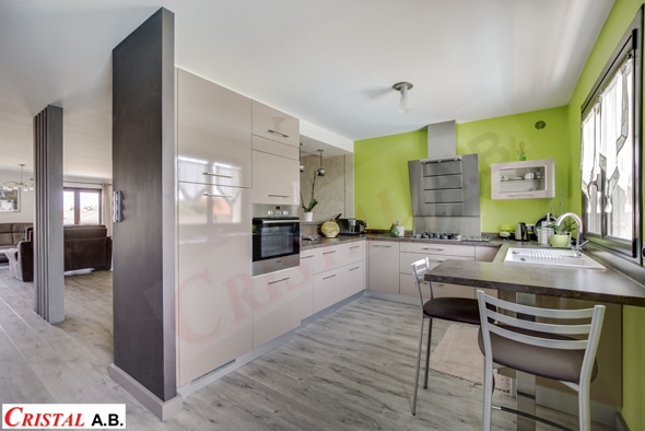 Cuisine moderne beige avec mur vert pomme, électroménager inox et coin repas CRISTAL A.B.