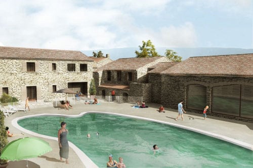 Vacanciers autour d'une piscine et maisons en pierre traditionnelles sous un ciel clair dans un complexe de vacances.