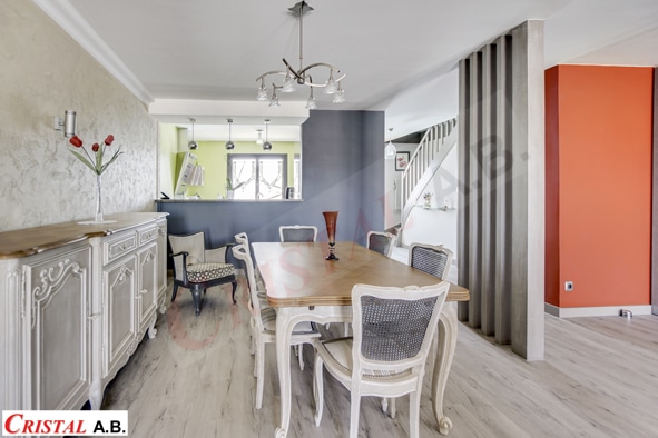 Salle à manger lumineuse avec table en bois, chaises médaillon et buffet blanc. Logo Cristal A.B. visible.