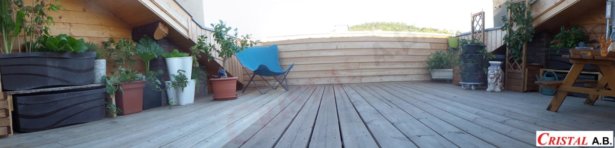 Terrasse en bois avec plantes en pots, chaise bleue et mobilier de jardin signés CRISTAL A.B.