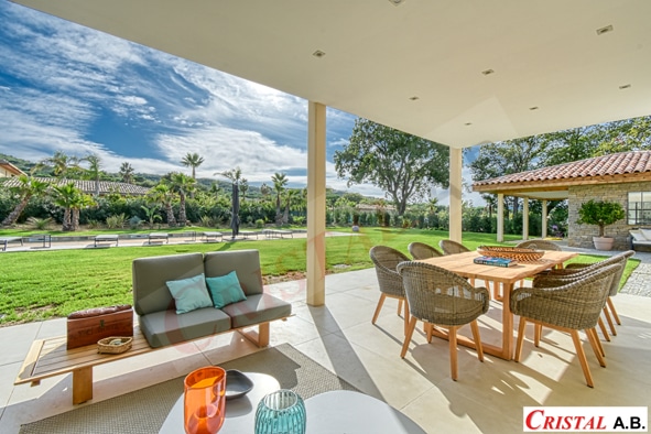 Terrasse de villa avec salon de jardin, table à manger et vue sur piscine. Logo Cristal A.B.